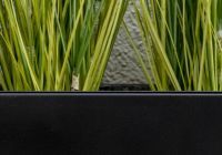 a close up of a black fiberglass planter with ornamental grasses